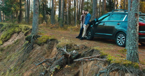 Couple-leaning-on-car-admire-forest-view-4K